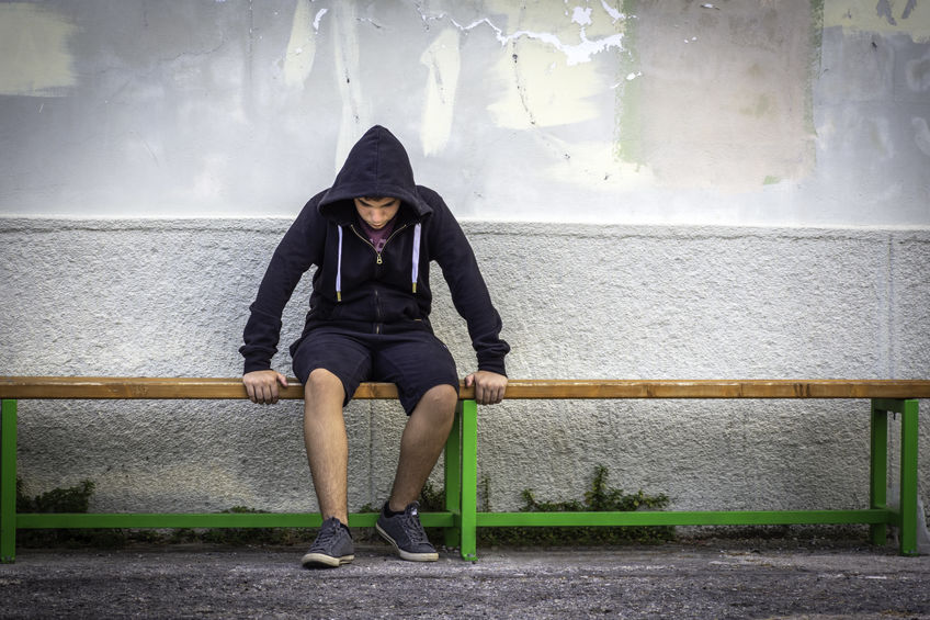 Little boy sad sitting alone at school hides his face